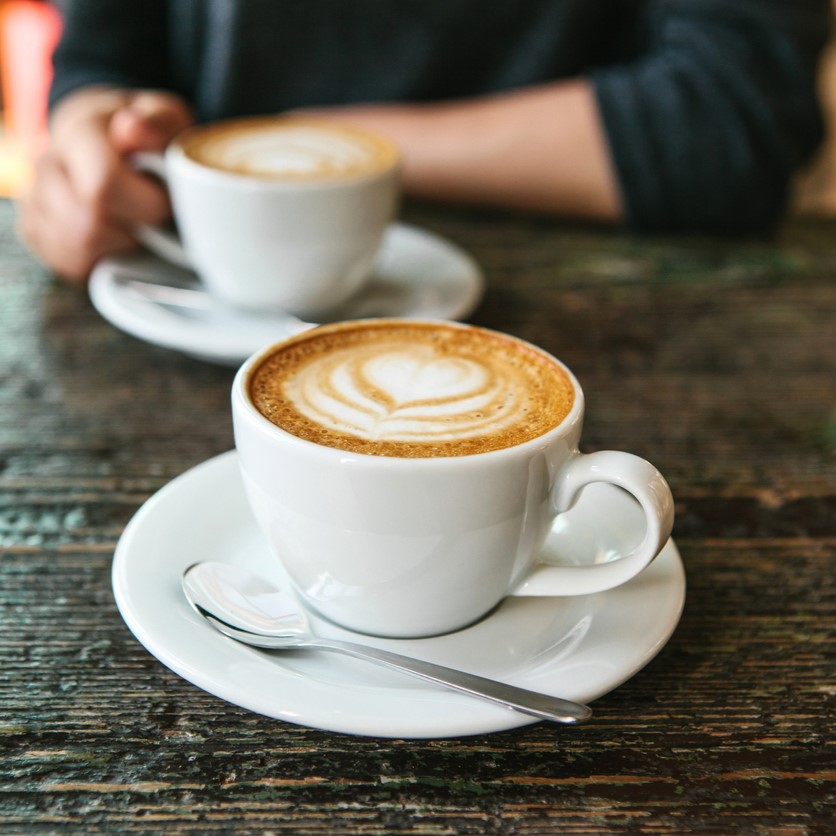 Zwei volle Kaffeetassen auf Holztisch