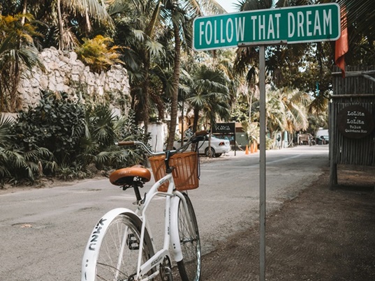 Weißes Fahrrad und Schild 'Follow that Dream'